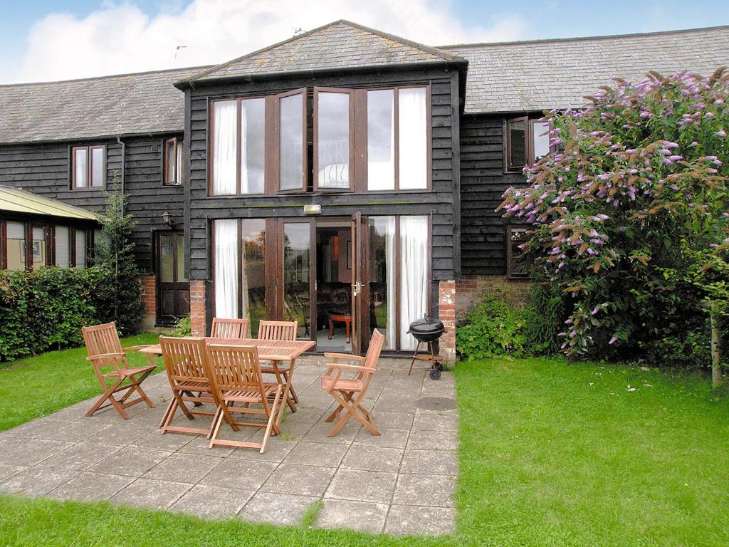 Un patio con una mesa y sillas frente a una casa. en Oldfield, en Warminster