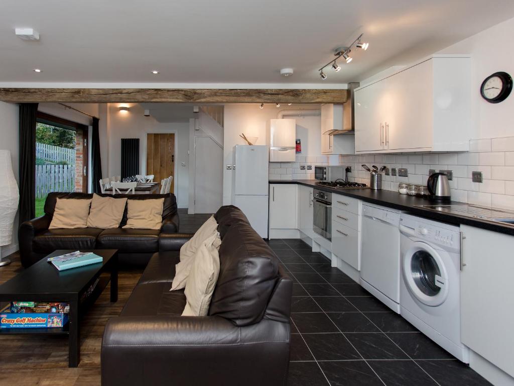 een woonkamer met een bank en een keuken bij Willow Barn - Fernhill Farm in Wootton Bridge