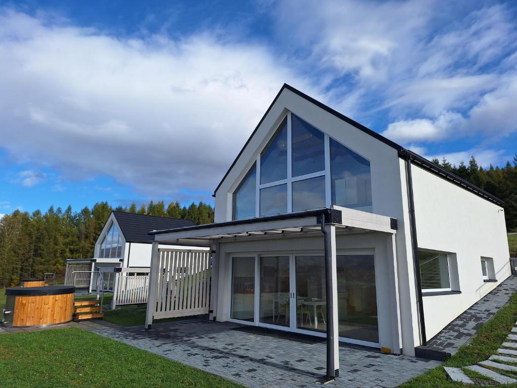 una casa bianca con una grande porta a vetri di Willa Biały Dereń z balią na wyłączność a Milówka