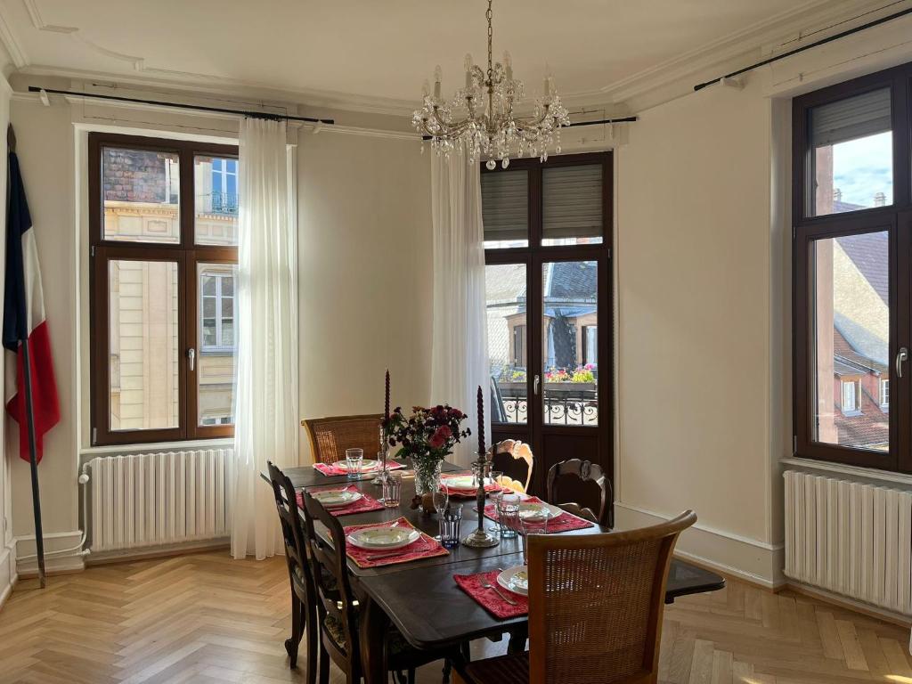 een eetkamer met een tafel, stoelen en ramen bij Apparemment de style 70s in Colmar