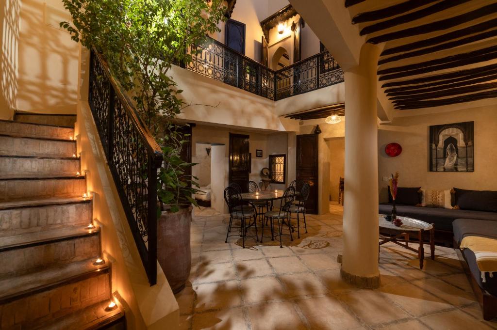 ein Wohnzimmer mit einer Treppe und einem Tisch und Stühlen in der Unterkunft Riad Privé Dar El Khamsa-Petit Dej inclus in Marrakesch