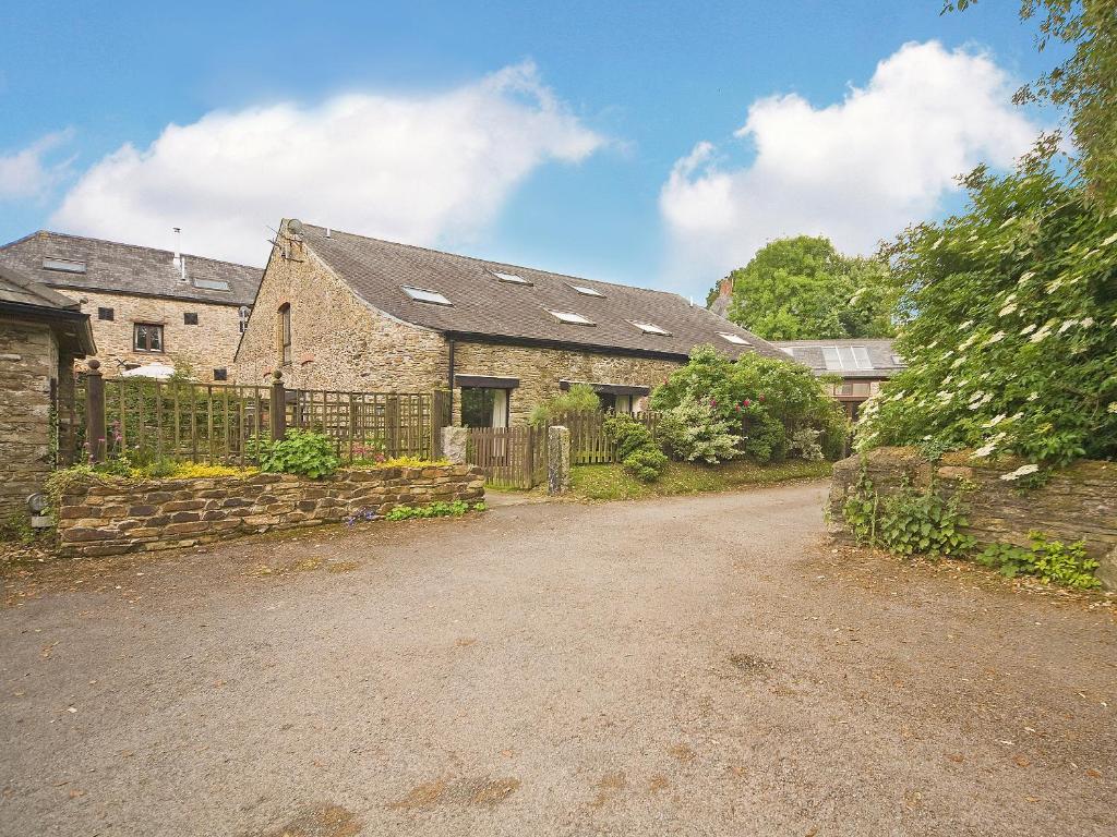 een oud stenen huis met een poort en een onverharde weg bij Dray Cottage in East Allington