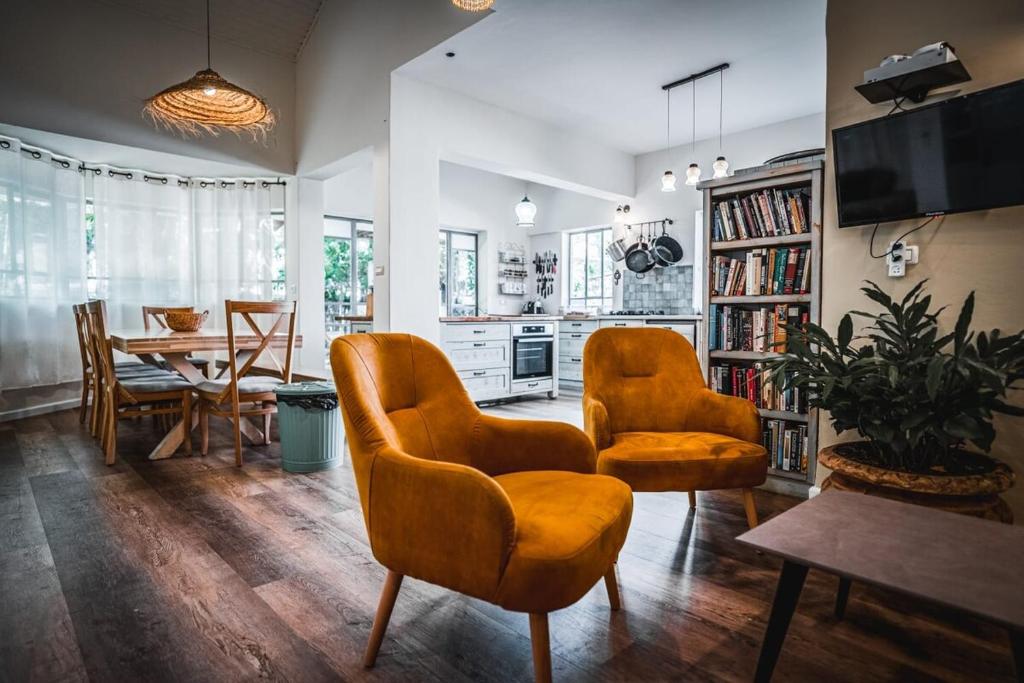 a living room with two chairs and a dining room at וילה בקיבוץ דפנה - אירוח וטיולים בלב טבע פראי in Metsudat Menahem Ussishkin Alef