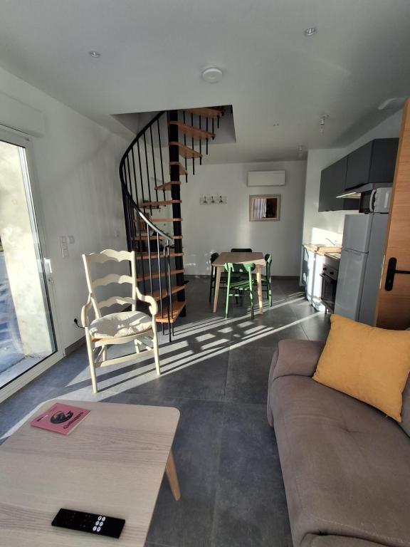 a living room with a couch and a spiral staircase at Gîte du Papillon CALUTRE in Carvin