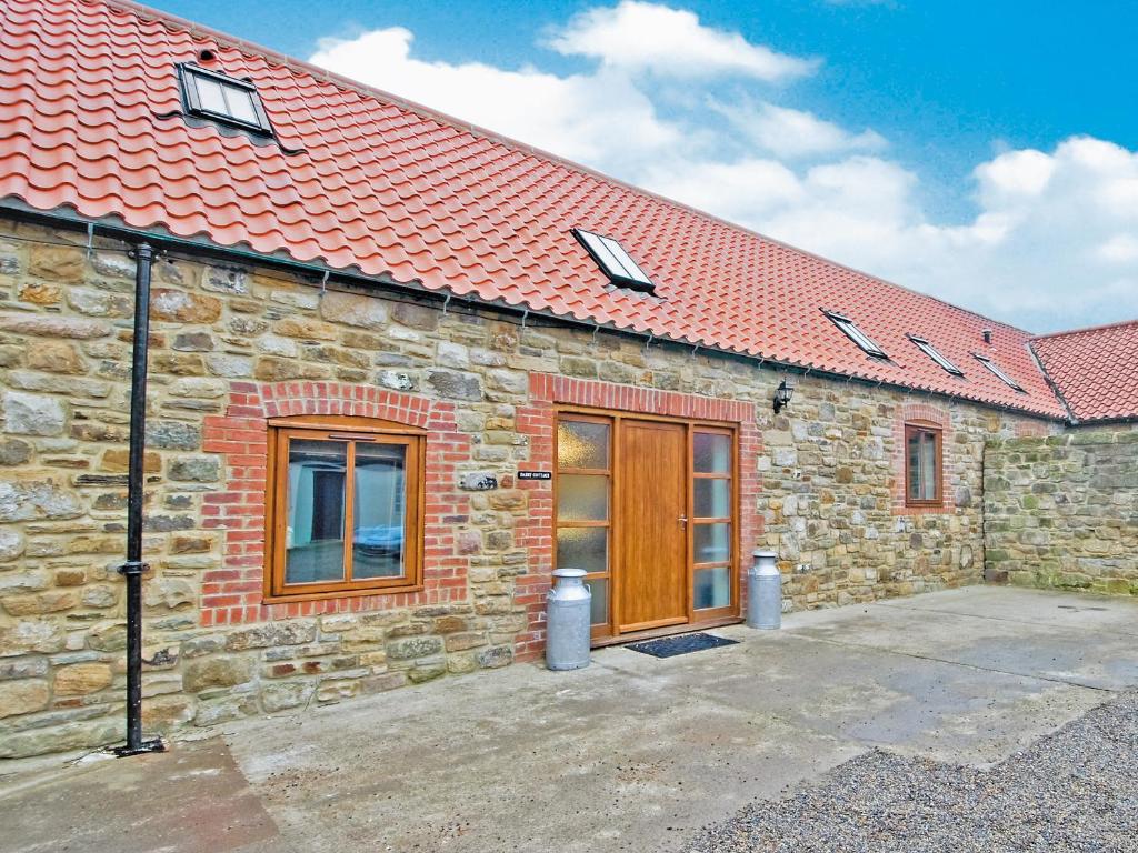 un bâtiment en pierre avec une porte en bois et un toit rouge dans l'établissement Dairy Cottage - E5279, à Shincliffe