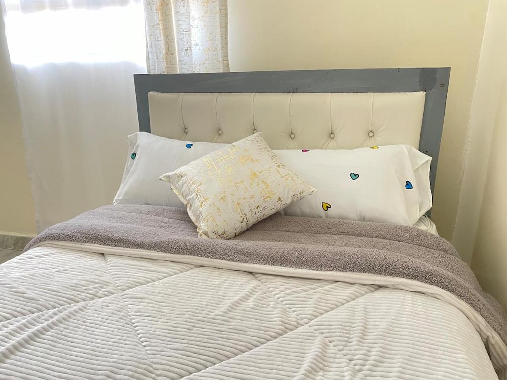 a bed with a white comforter and pillows at Calm getaway in Rongai in Ongata Rongai 