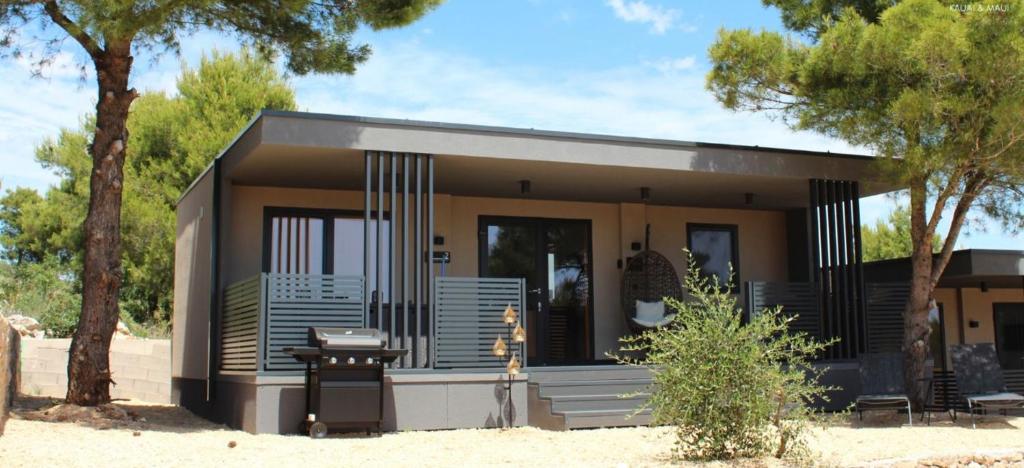 a small house with a porch and trees at Maui, Kamp Heron, Drage, Croatia in Drage