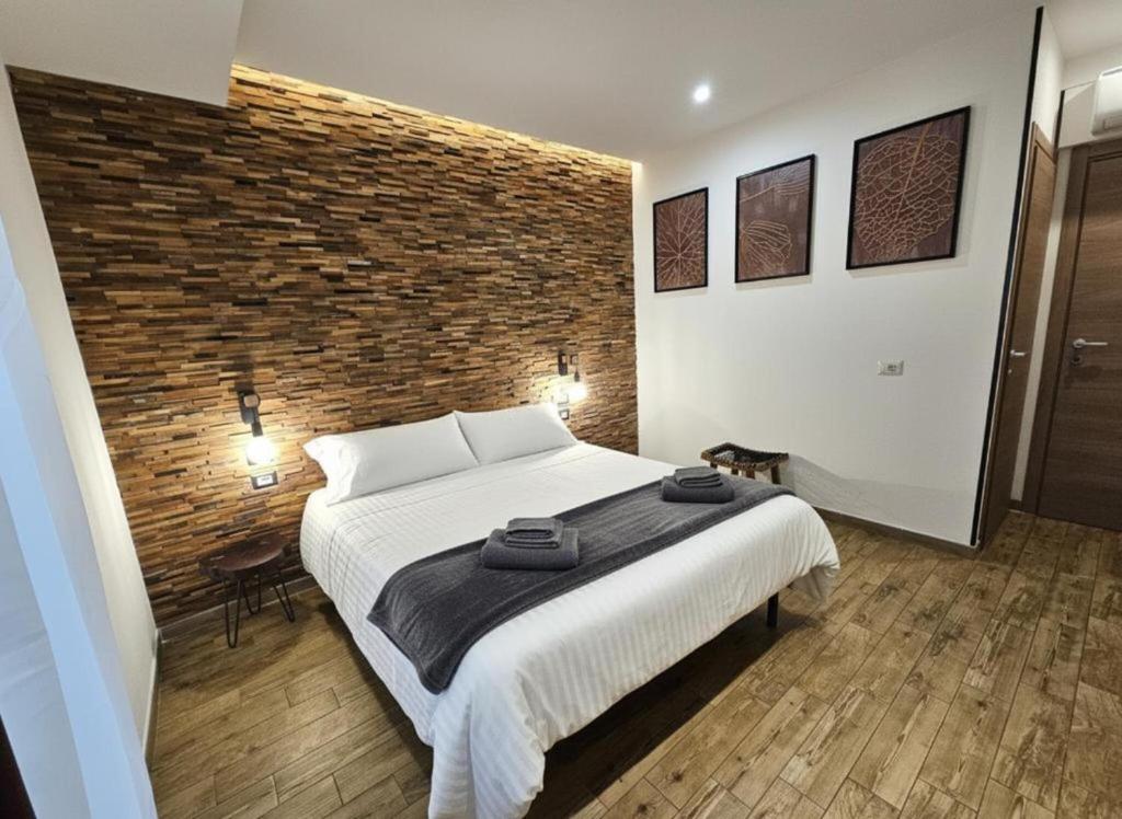 um quarto com uma cama grande e uma parede de tijolos em ARYA Cagliari em Cagliari