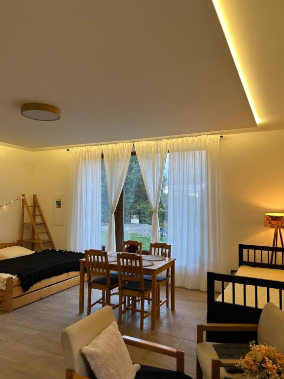 een woonkamer met een tafel, stoelen en een bed bij Dům mezi loukami in Sněžné