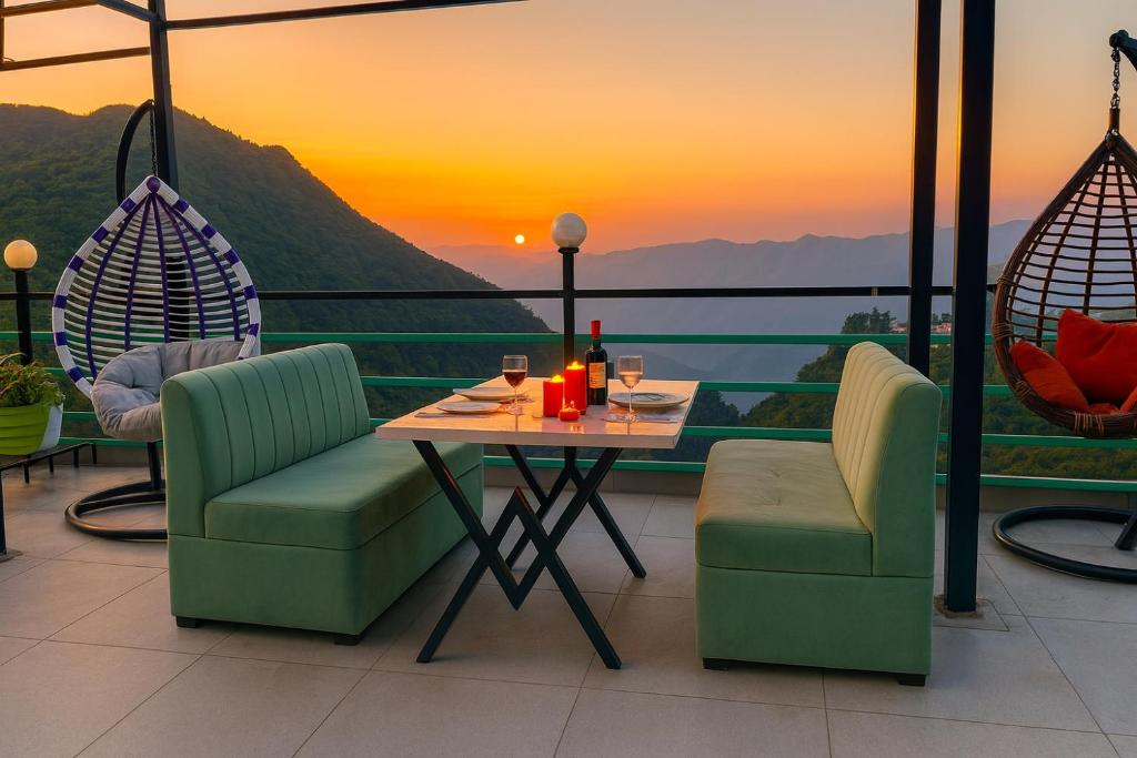 a table and chairs on a balcony with a sunset at Doon Nature Valley Resort, Mussoorie in Mussoorie