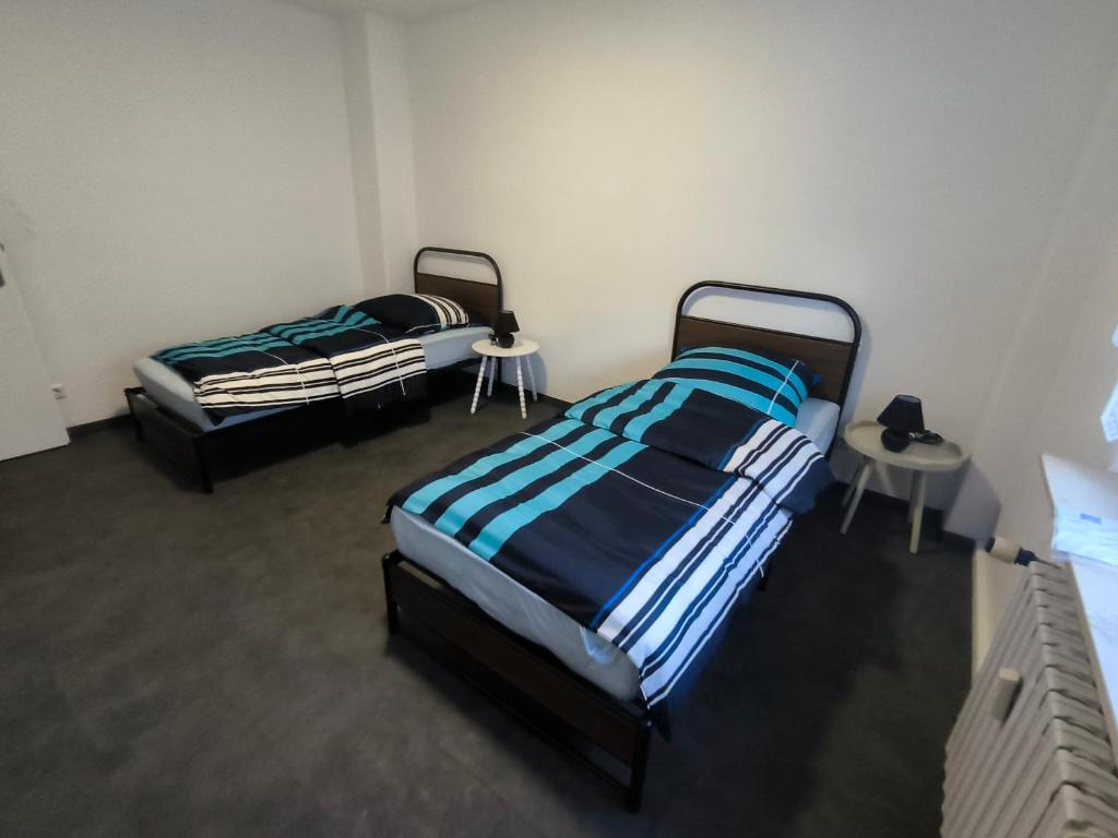 twee bedden in een kamer met twee tafels bij Mego Unterkünfte in Bönen