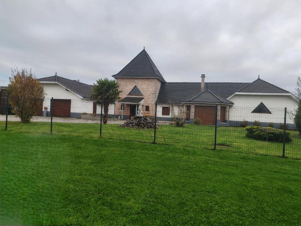 a house with a fence in front of a yard at Gîte du Tronquoy in Aix-en-Ergny