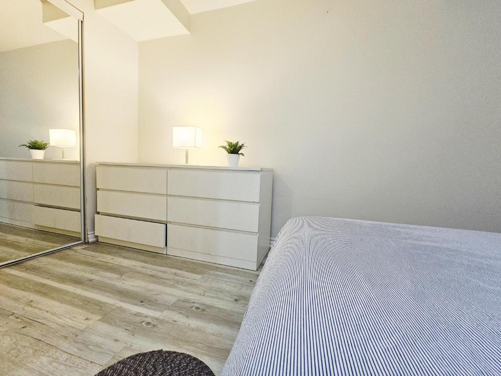 a white bedroom with a bed and a mirror at Garden Ave Suite 3 Mins to Hwy 403 in Brantford