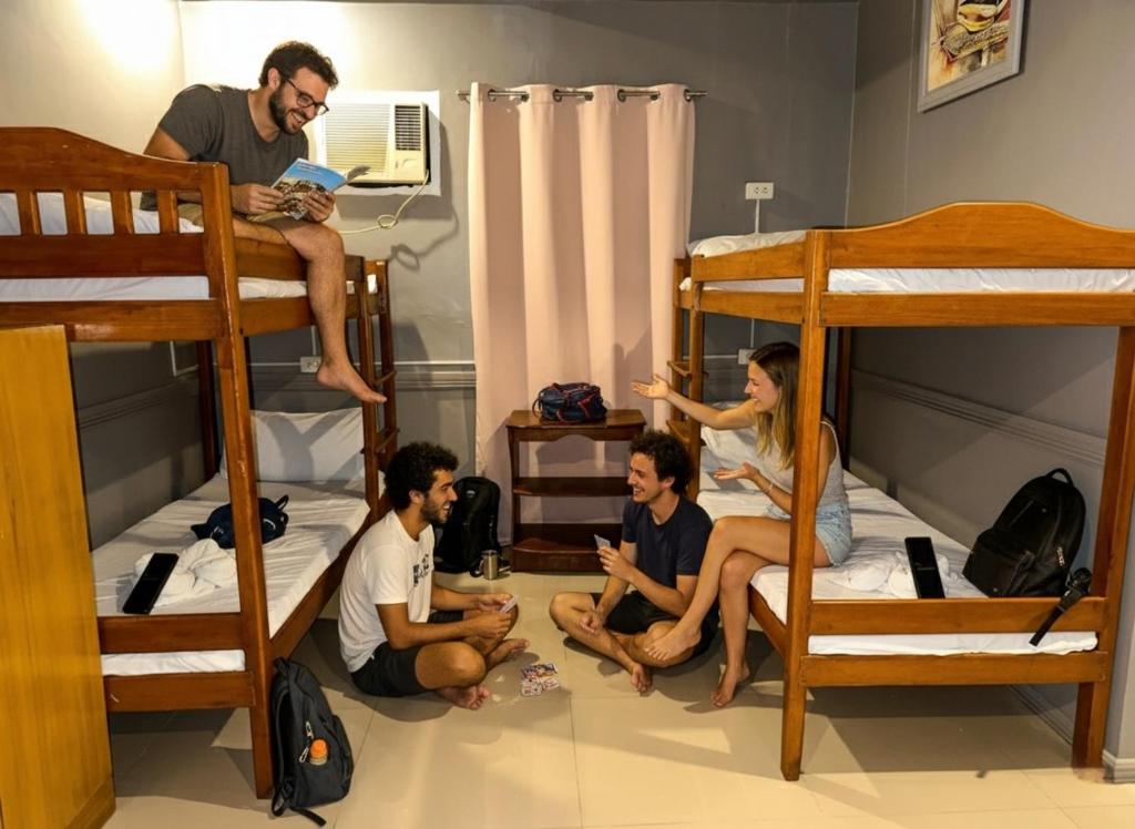 a group of people sitting in a room with bunk beds at Hola Hostel Puerto Princesa in Puerto Princesa City