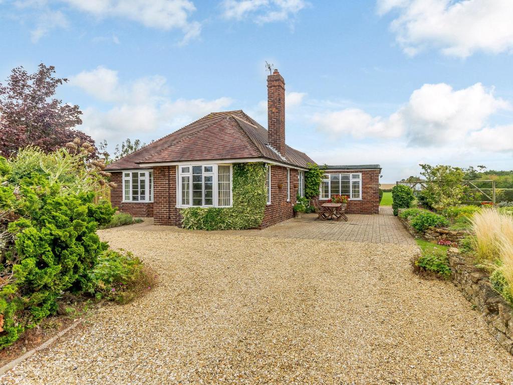 a brick house with a chimney on a gravel driveway at Henrys Retreat in Ingoldsby