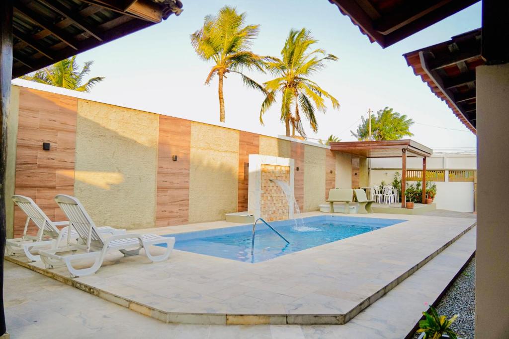 a swimming pool with chairs and a house at Residência Lençóis Pousada in Barreirinhas