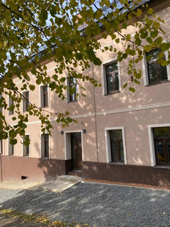 un edificio con ventanas y un árbol delante de él en Apartmány Mikulov 45, en Mikulov v Krušných Horách