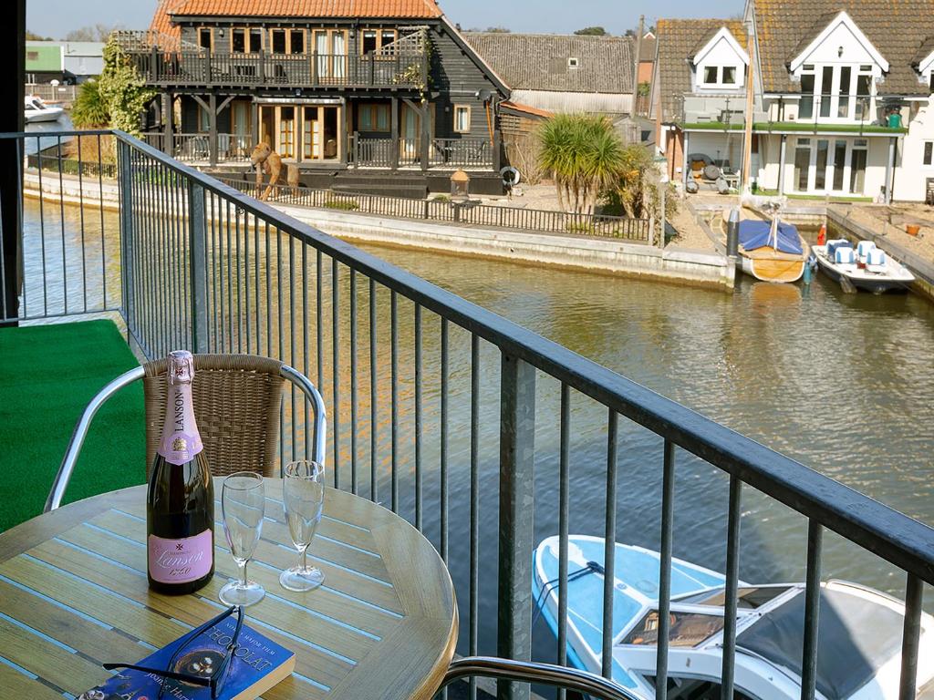 a table with two glasses and a bottle of wine on a balcony at Coot in Wroxham