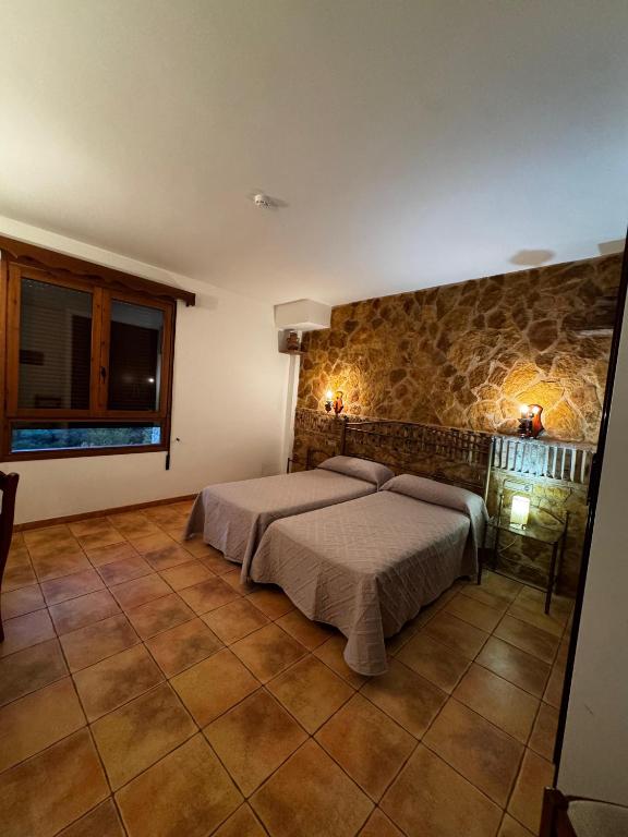 a bedroom with a bed and a stone wall at Hostal Todolella in Todolella