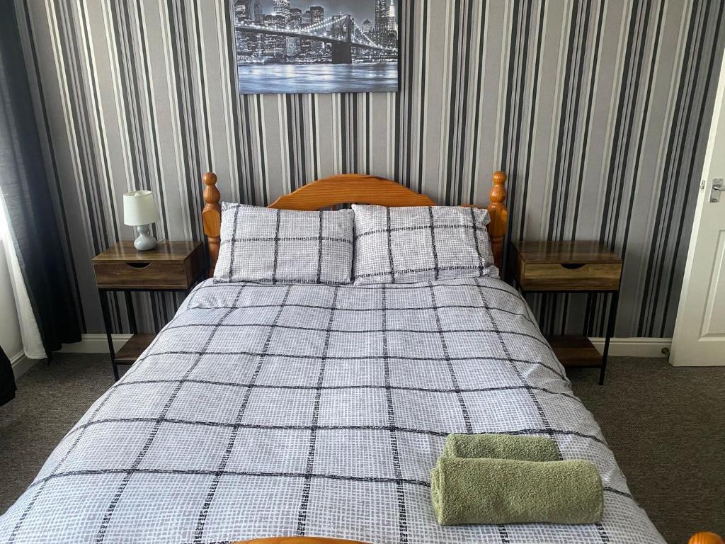 a bed with a checkered blanket and pillows at Spacious Property For Hols Base & Contractors Long or Short Stays C2C Western Lakes in Cleator Moor