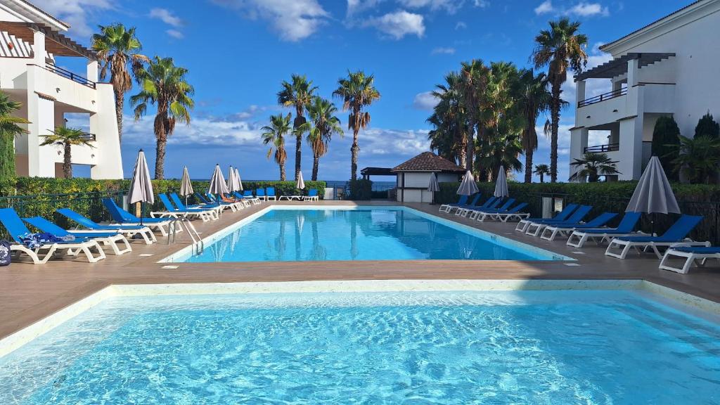 ein Swimmingpool mit Stühlen und einem Gebäude in der Unterkunft Appartement dans résidence avec piscine et plage privées in San-Nicolao