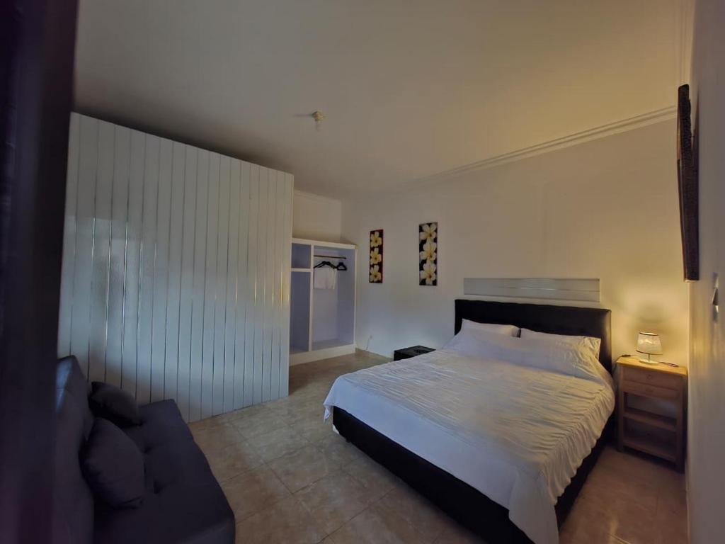 a bedroom with a bed and a couch at Hillside guest house and restaurant in Gitgit