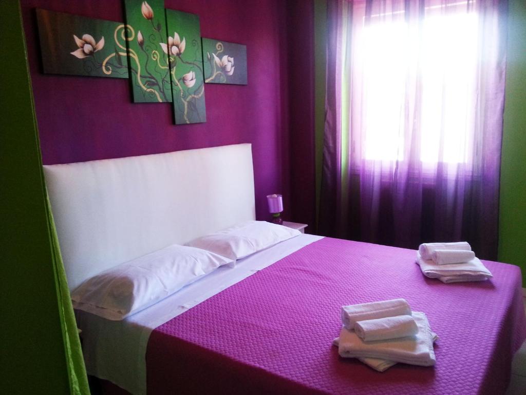 a bedroom with a pink bed with towels on it at B&B Night & Day in Cosenza