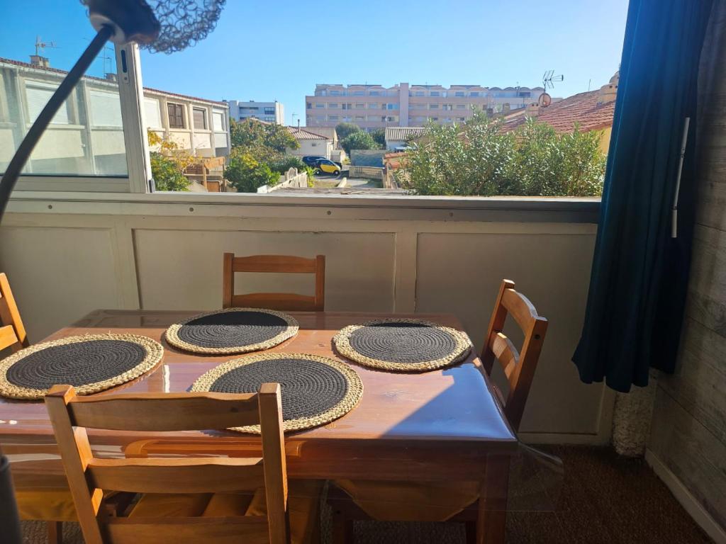 une table à manger avec quatre chaises et une fenêtre dans l'établissement PALMA II, à Port-la-Nouvelle