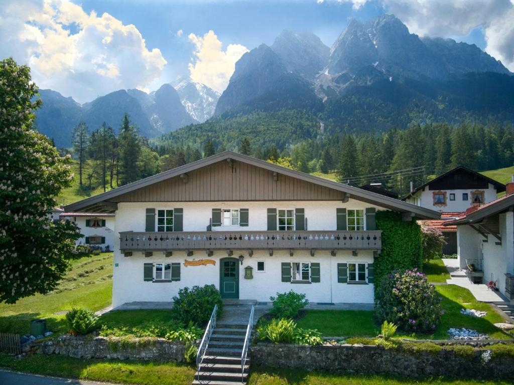 a large white house with mountains in the background at Alpine Chalet Apartment With Zugspitze Views in Grainau