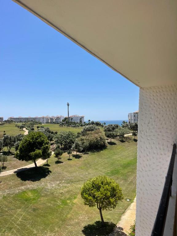 Blick auf einen Park mit Bäumen und ein Gebäude in der Unterkunft Assilah marina golf 32 in Asilah