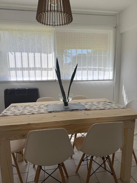 a dining room table with chairs and a vase with feathers at Departamento impecable! in Azul