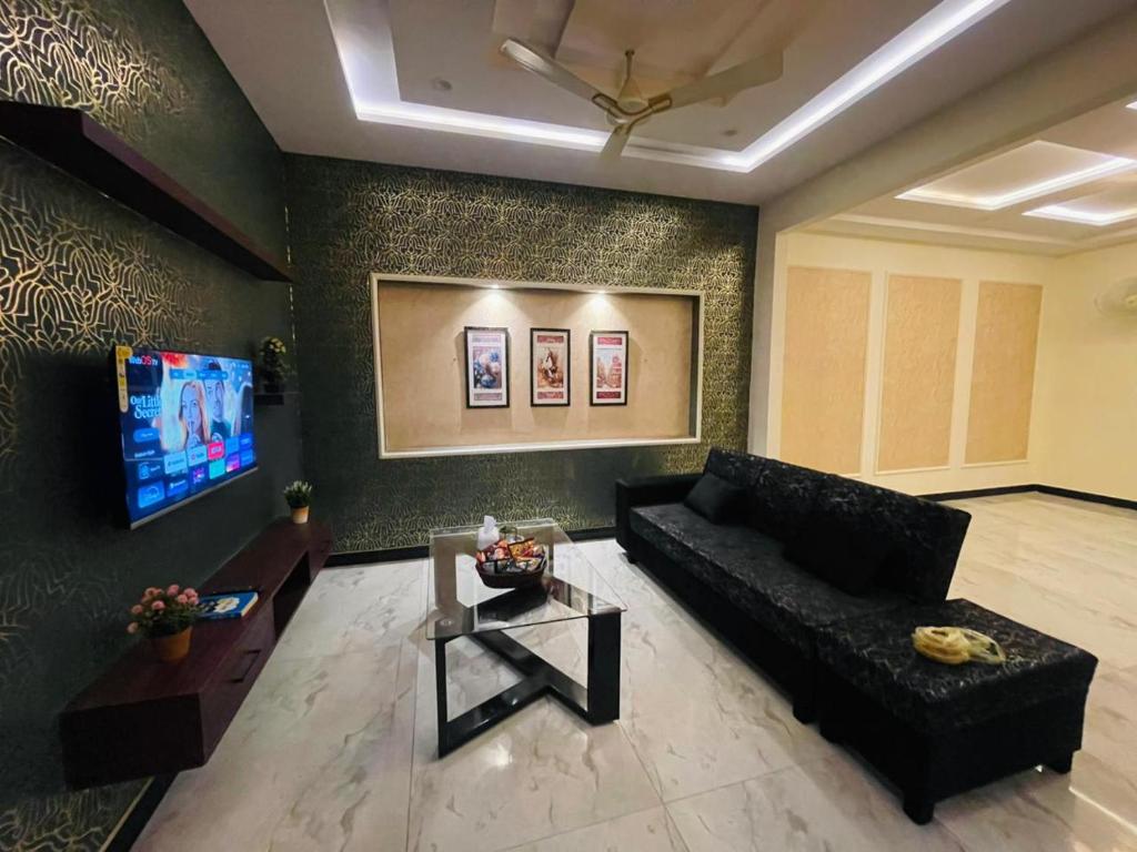 een woonkamer met een zwarte bank en een tafel bij Luxury home in Multan in Multan