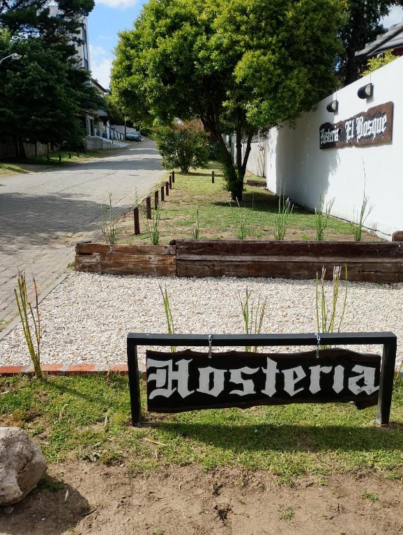 a sign sitting in the grass next to a street at Hostería El Bosque in Villa Gesell