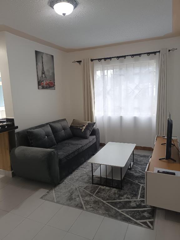 a living room with a couch and a table at 1 bedroom BNB Meru in Meru