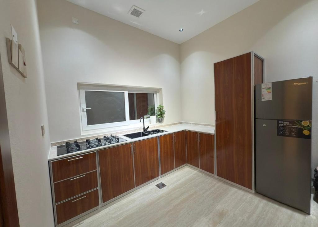 Una cocina con refrigerador de acero inoxidable y ventana. en Roma chalet استراحة روما بدية, en Al Raka