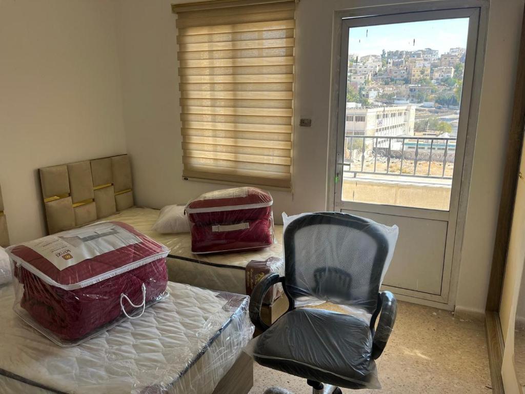 a room with two beds and a chair and a window at 2 Bedroom apartment in Jerash Centre in Jerash