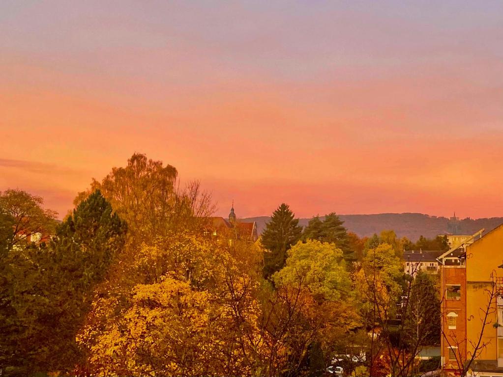 a sunset over a city with trees and buildings at Cosy Sunset Flat - Kongress Palais & Herkules View in Kassel