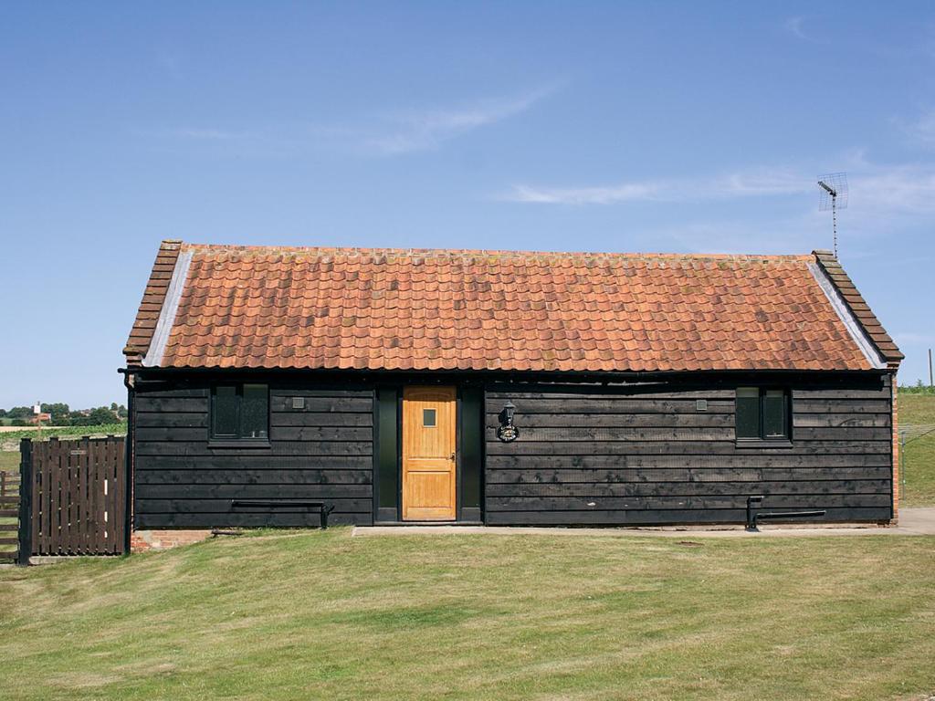 a small black building with a brown roof at Carol's Cottage - E3043 in Blyford