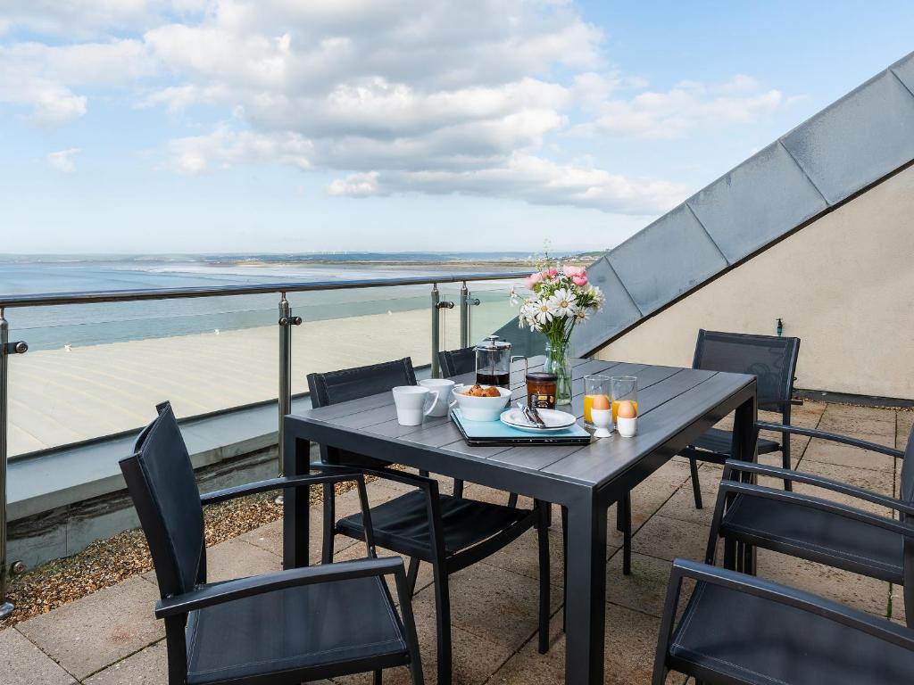 einen Tisch und Stühle auf einem Balkon mit Blick auf den Strand in der Unterkunft Sand Dunes in Westward Ho