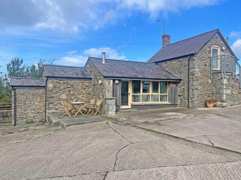 una casa de piedra con una mesa de picnic delante de ella en Little Barn - Hw7615, en Bettws-yn-Rhôs