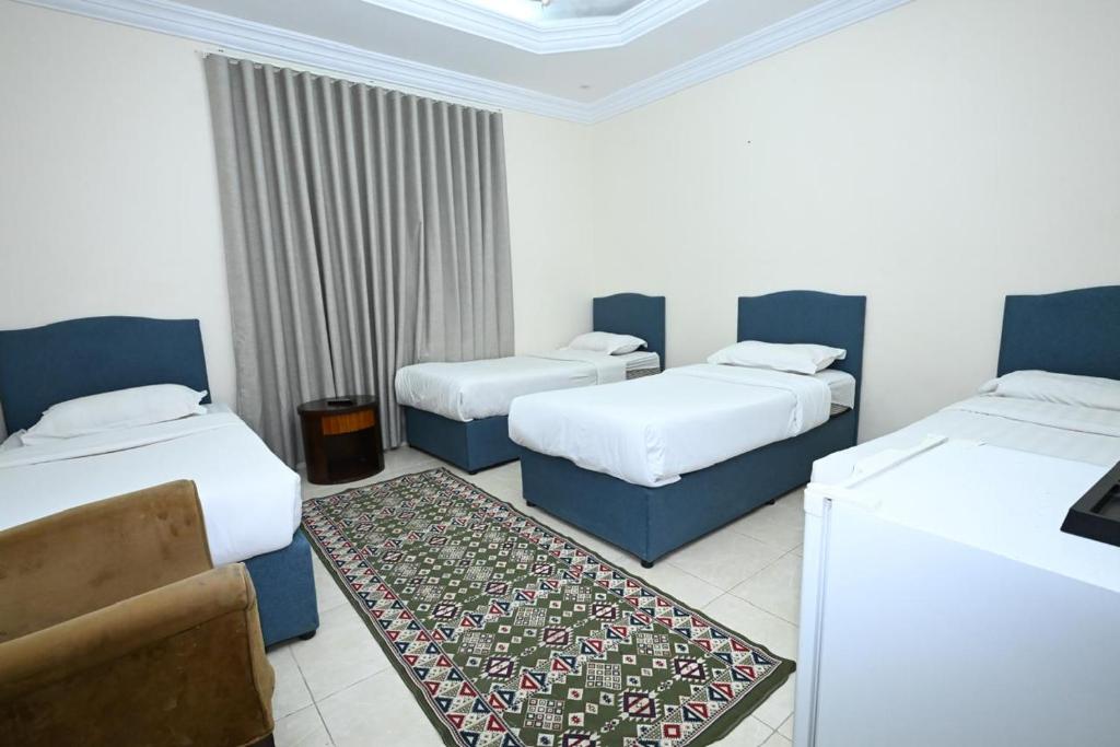 a hotel room with three beds and a couch at بيت سلسبيل in Al Madinah