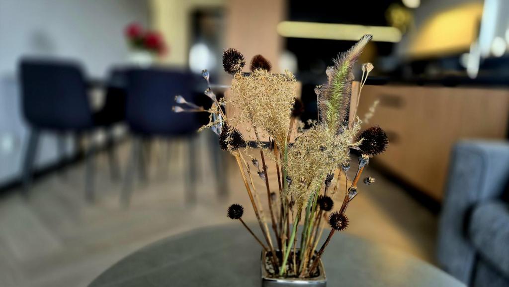 un vase avec des fleurs séchées assises sur une table dans l'établissement Apartamenty Graniczna 1, à Rzeszów
