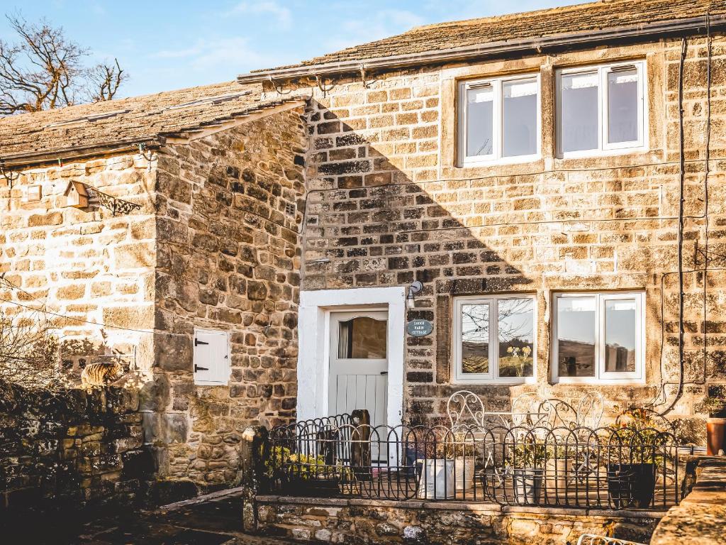 an old brick house with a white door at Lodge Farm Cottage in Haworth