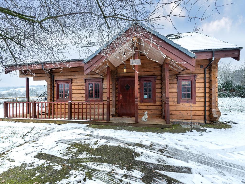 a log cabin in the snow with a dog in front at Ty Ceirios - Uk42100 in Carno