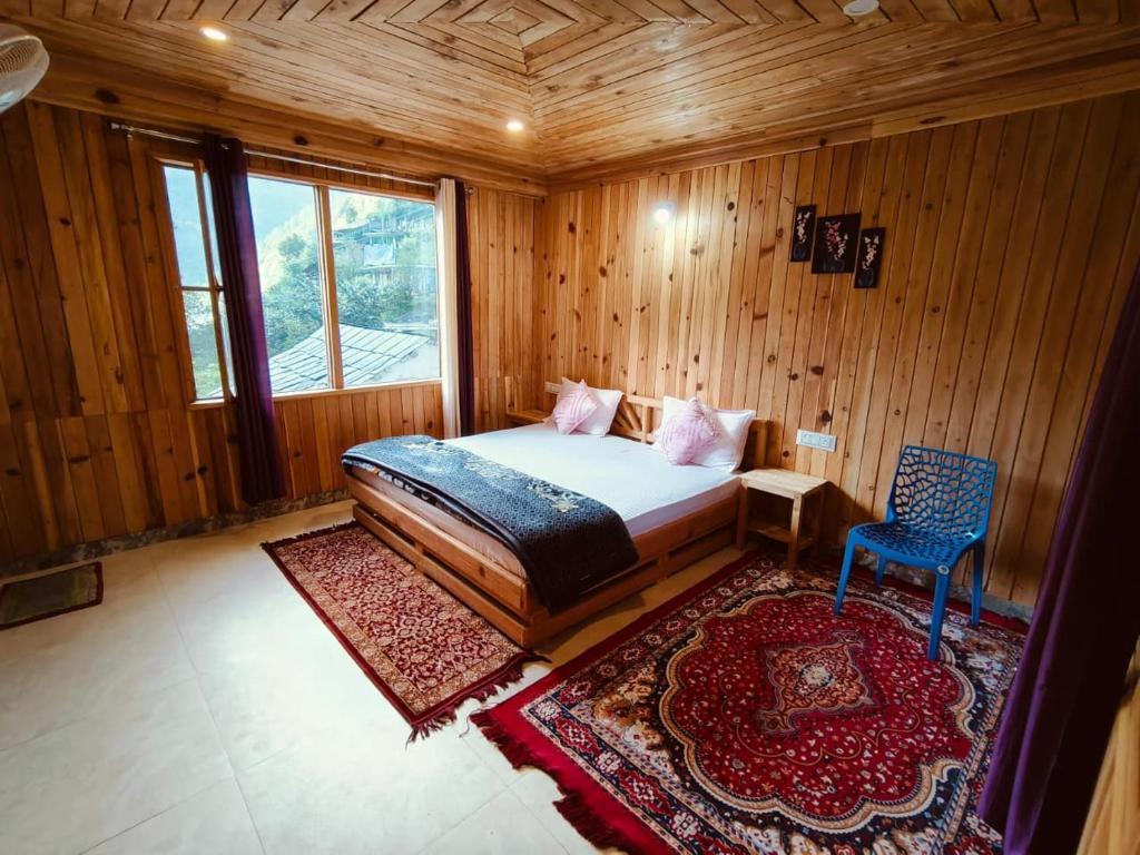 a bedroom with a bed and a chair in a room at Tirthan Majestic View Homestay in Kulu