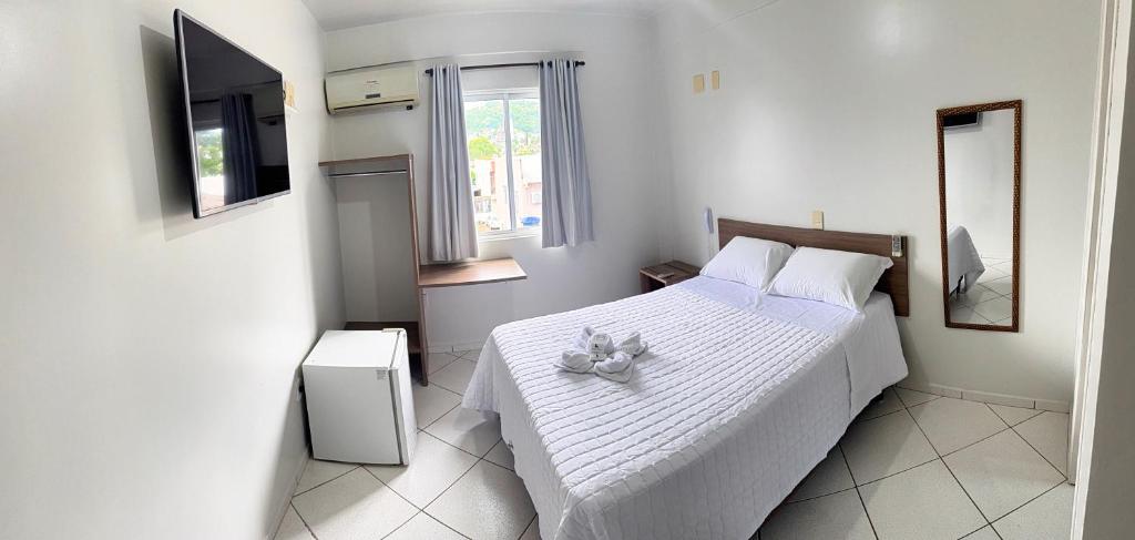 een slaapkamer met een wit bed met een teddybeer erop bij Hotel Ideal Beltrão in Francisco Beltrão