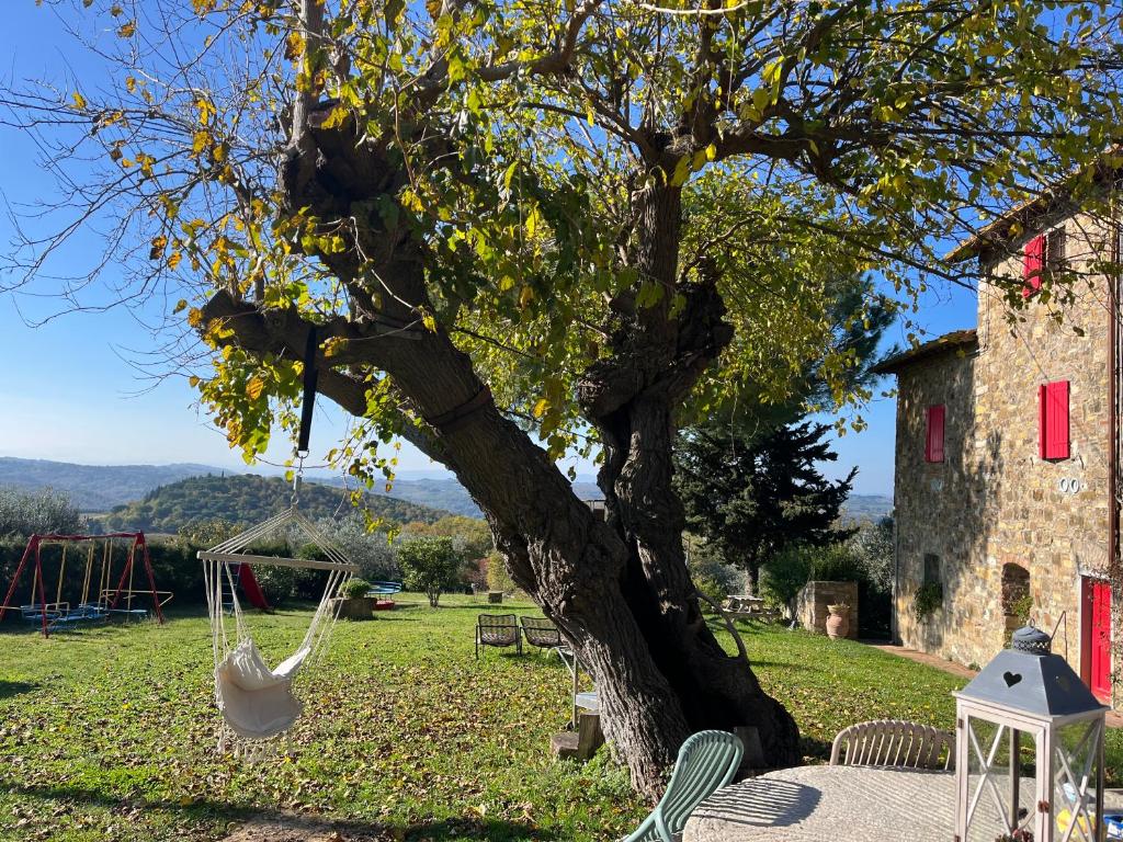 a swing hanging from a tree next to a building at Il Fiorino di Badia in Badia A Passignano