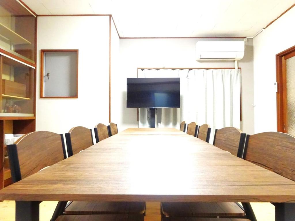 a conference room with a wooden table and chairs at 豊橋南栄駅徒歩1分 最大9名一棟貸 ホタルヤ Guest House Hotaruya Toyohashi Minami Sakae in Toyohashi