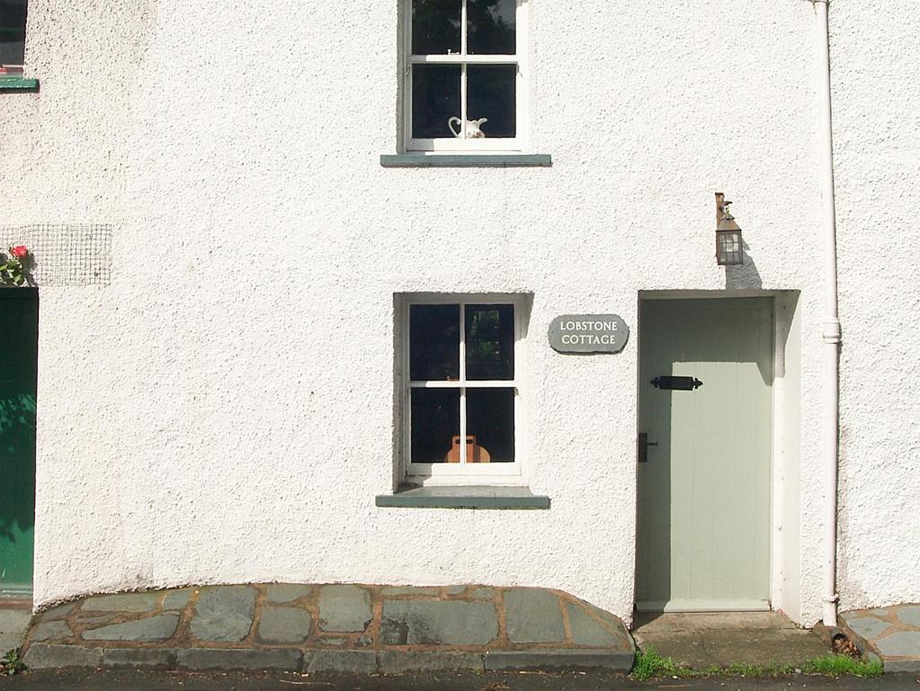 - un bâtiment blanc avec une fenêtre et une porte dans l'établissement Lobstone Cottage, à Rosthwaite