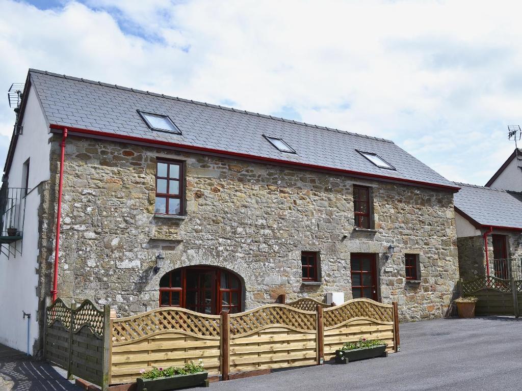 a stone building with a wooden fence in front of it at The Stables- Osb in Penbryn
